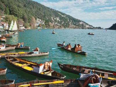 Wooden boats on Nainital Lake against lush hills, perfect for a serene getaway.