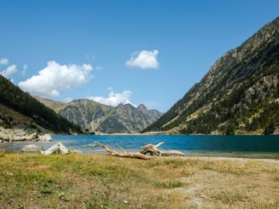 Serene view of a mountain lake surrounded by rocky peaks under a clear blue sky.